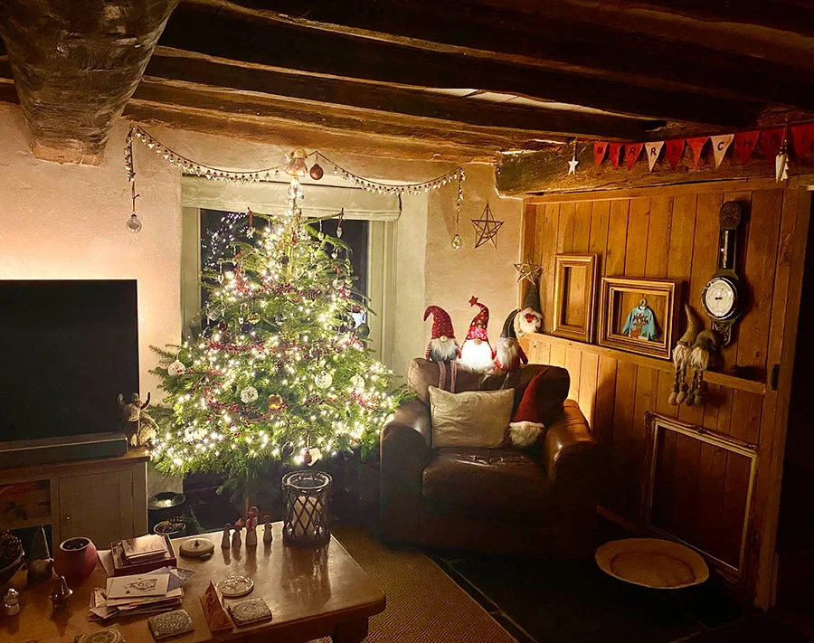 Cottage at Christmas The cozy cottage living room decorated for Christmas 2021, with a Christmas tree by the patio doors.