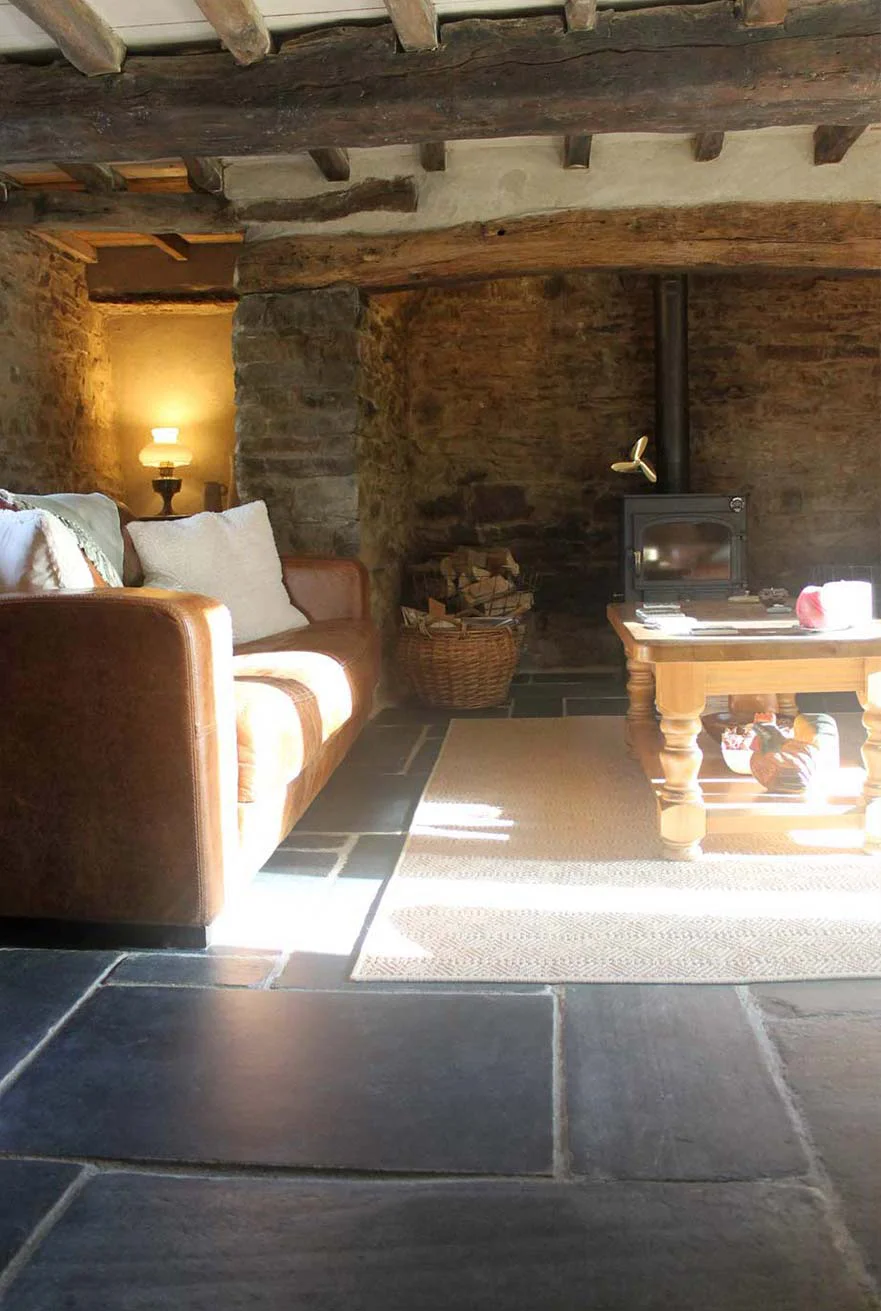 Cottage Living Room: Inglenook and Beams Interior view of the cottage living room, featuring the inglenook fireplace with a wood-burning stove and oak beams.