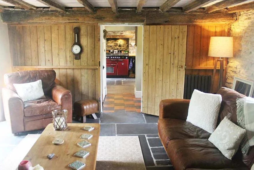 Cottage Interior: Hallway and Living Room View from the living room through the hallway towards the kitchen, showing Victorian floor tiles and wooden panelling.